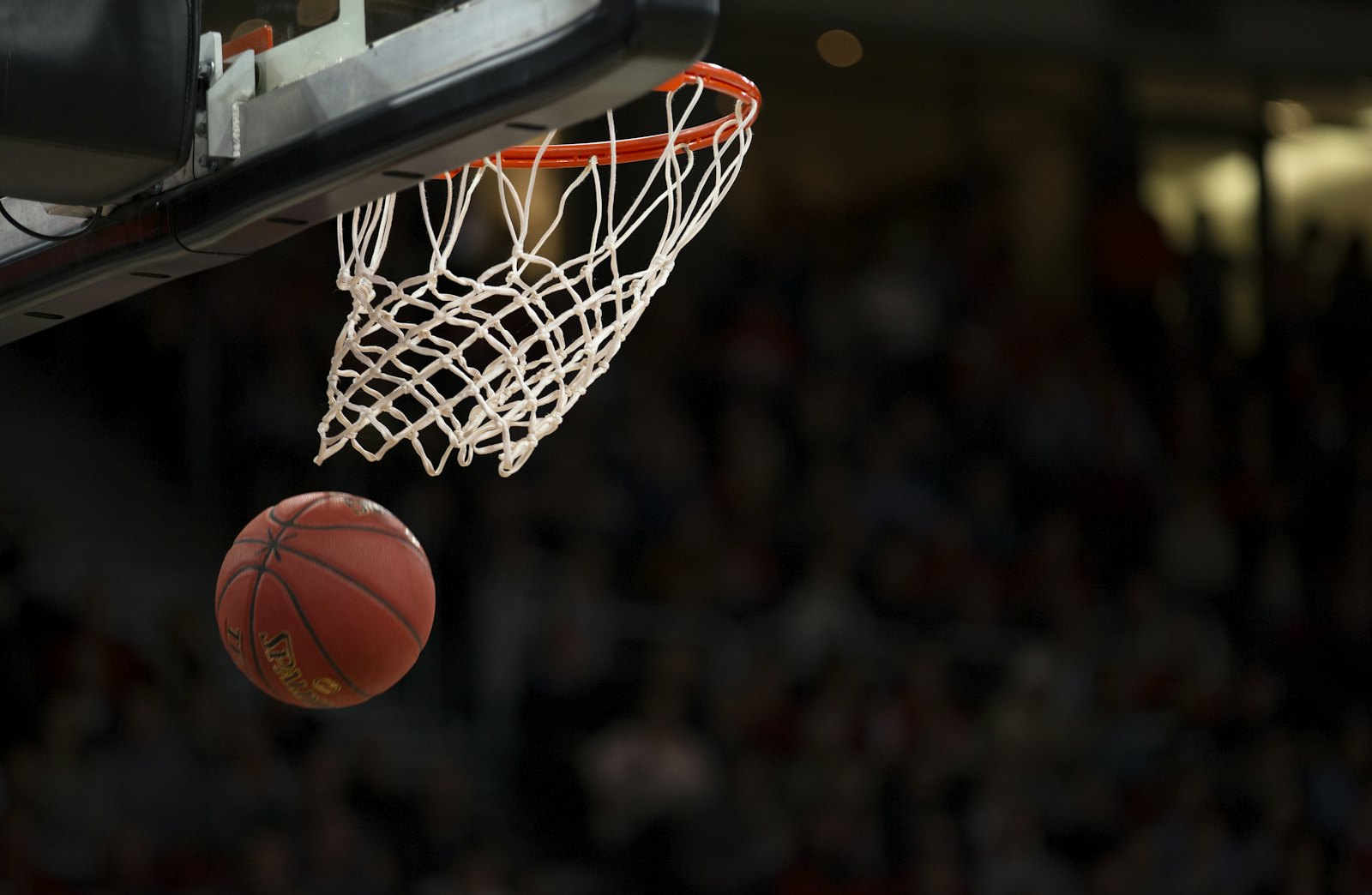 A basketball dropping through the net in a packed arena.